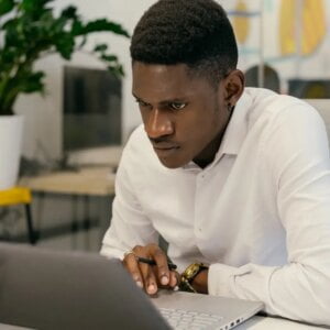Homem em vestimenta profissional segurando um laptop, simbolizando competência e confiabilidade no ambiente de marketing digital.