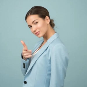 Mulher profissional em blazer azul acenando com o polegar para cima, endossando soluções de marketing eficazes.